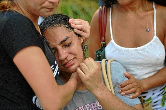 Moradora é consolada: prédios teriam sido erguidos por milícias (Carl de Souza/AFP)
