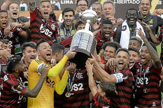 Diego Alves, Éverton e Diego erguem a taça, na tripla comemoração dos capitães da equipe durante a campanha. Jogadores entram para a história do clube com 2º título da Libertadores (Ernesto Benavides/AFP
)