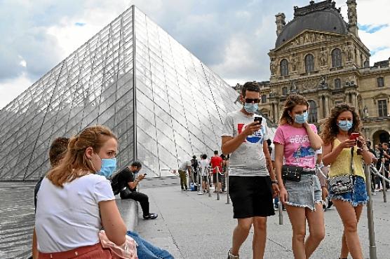 Turistas passam em frente ao Museu do Louvre, em Paris: fim gradativo das restrições (Bertrand Guay/AFP)