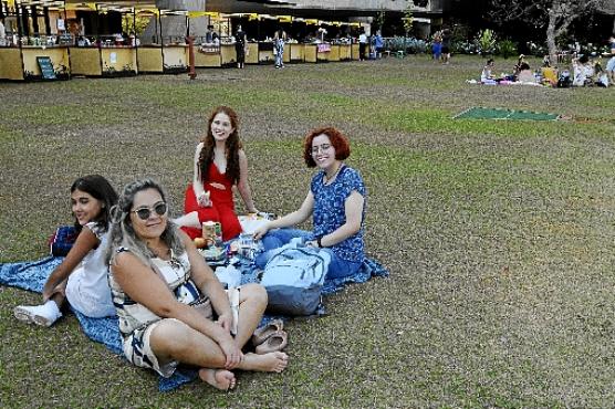 A família de Crislayne Nicácio (de vermelho) aproveitou a tarde de Sol para fazer um piquenique no gramado do CCBB