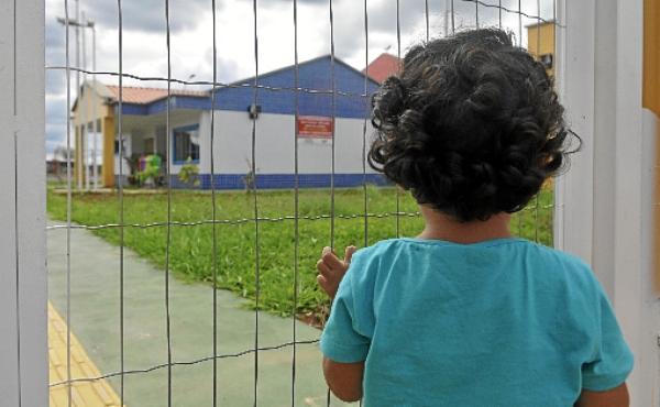 Pelo portão, criança observa uma creche fechada em  Samambaia  (Minervino Junior/CB/D.A Press - 1/12/14 )